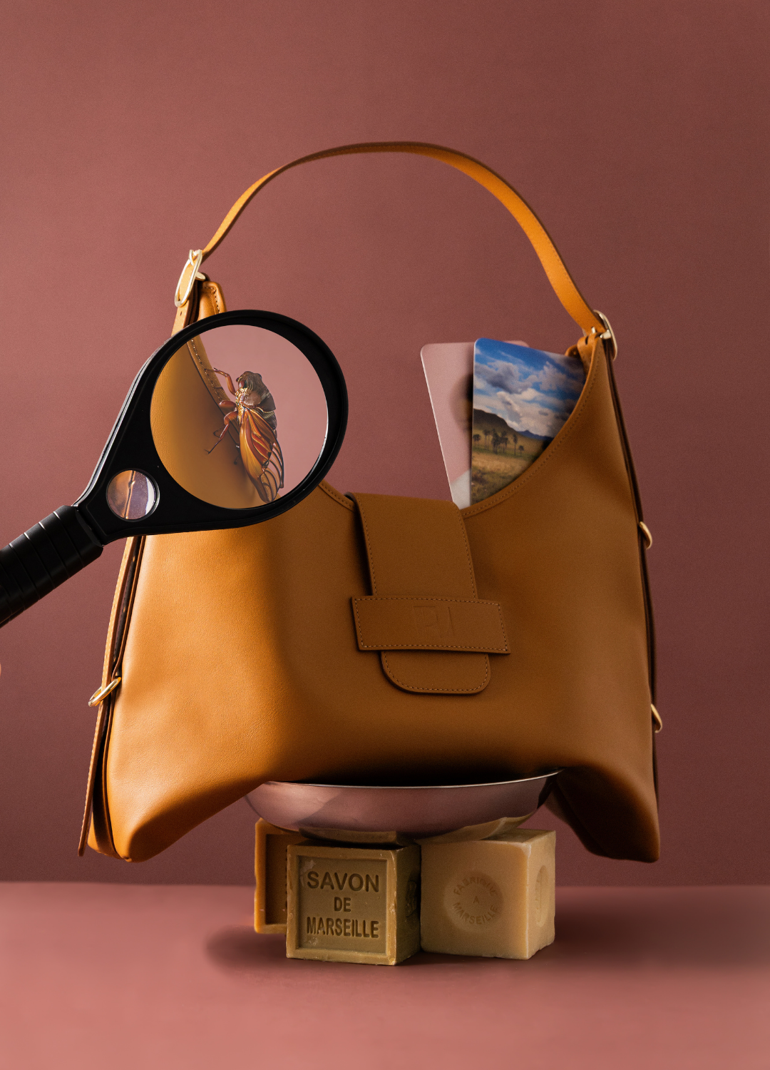 le sac fada taille L camel est mis en scène sur des savons de marseille. une cigale s'est posé dessus et une loupe l'observe