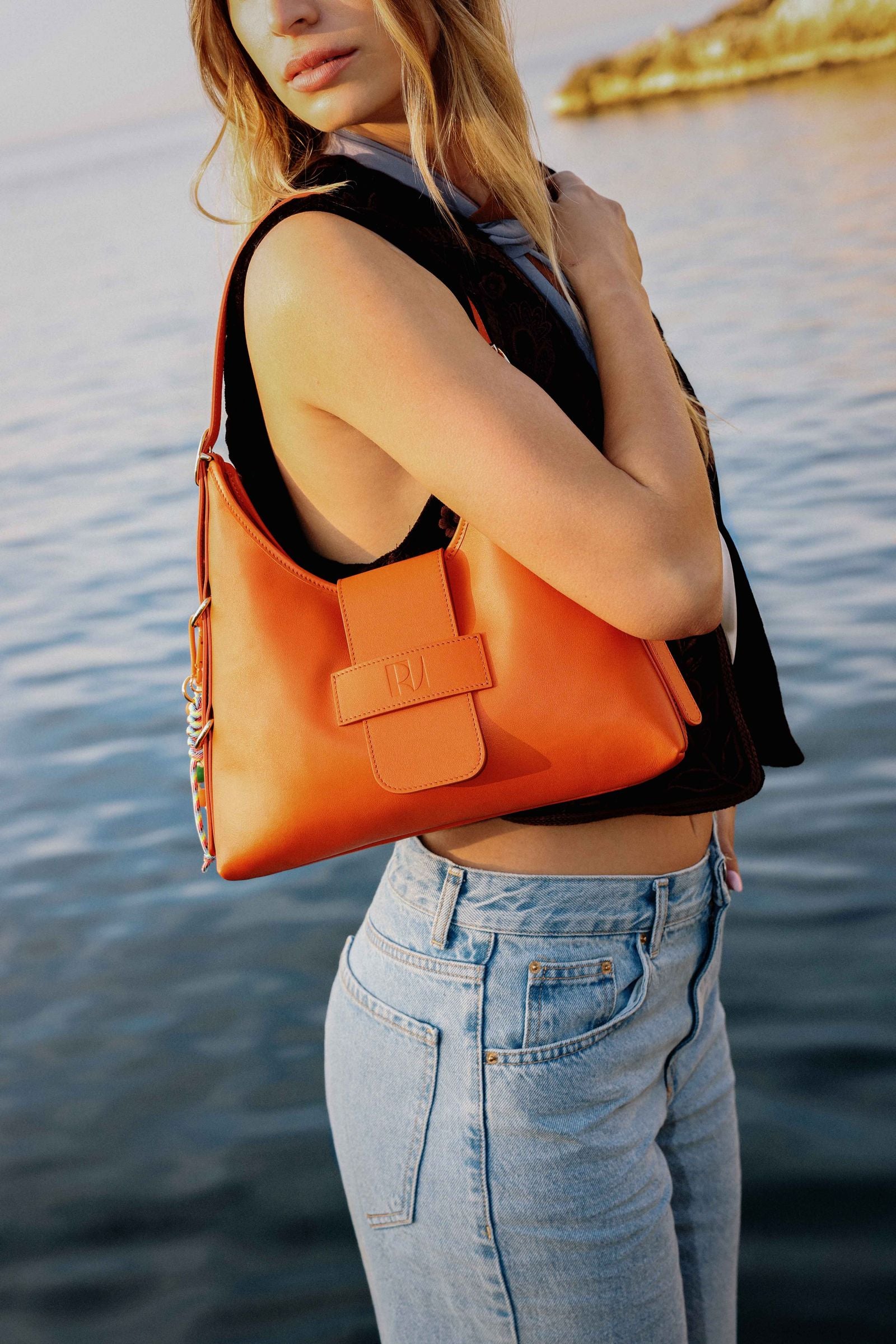 jeune femme portant à l'épaule le sac fada taille M orange devant la mer