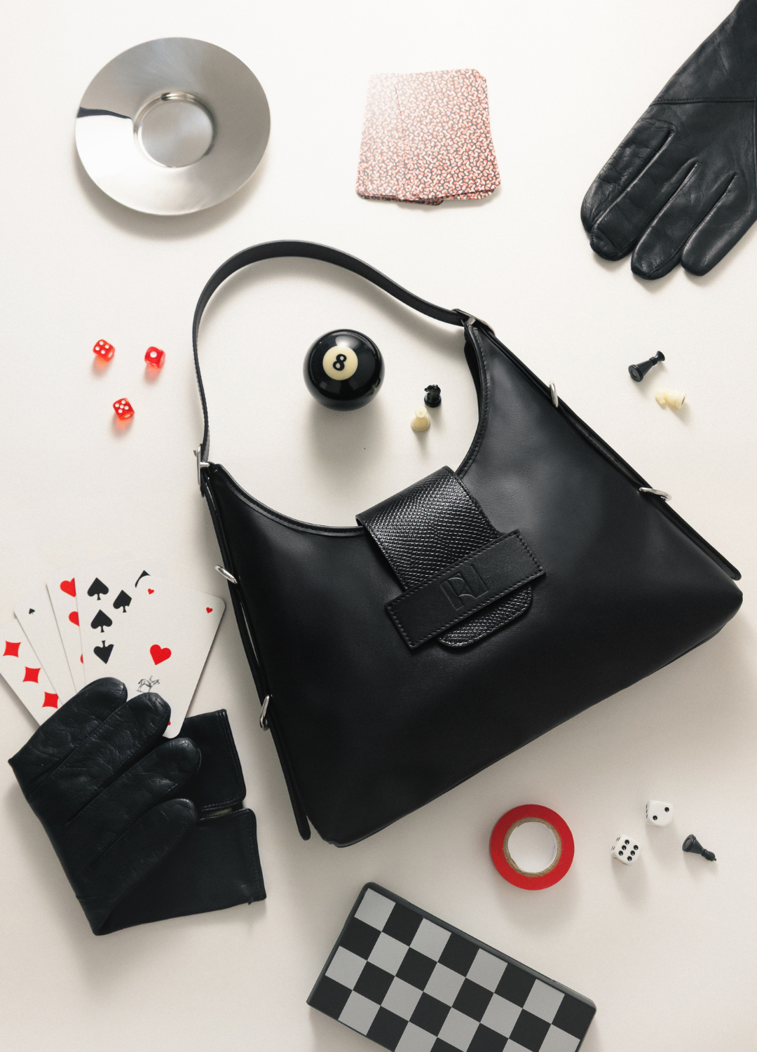 sac fada taille M mis en scène sur une table avec jeu de cartes, boule de billard, gants
