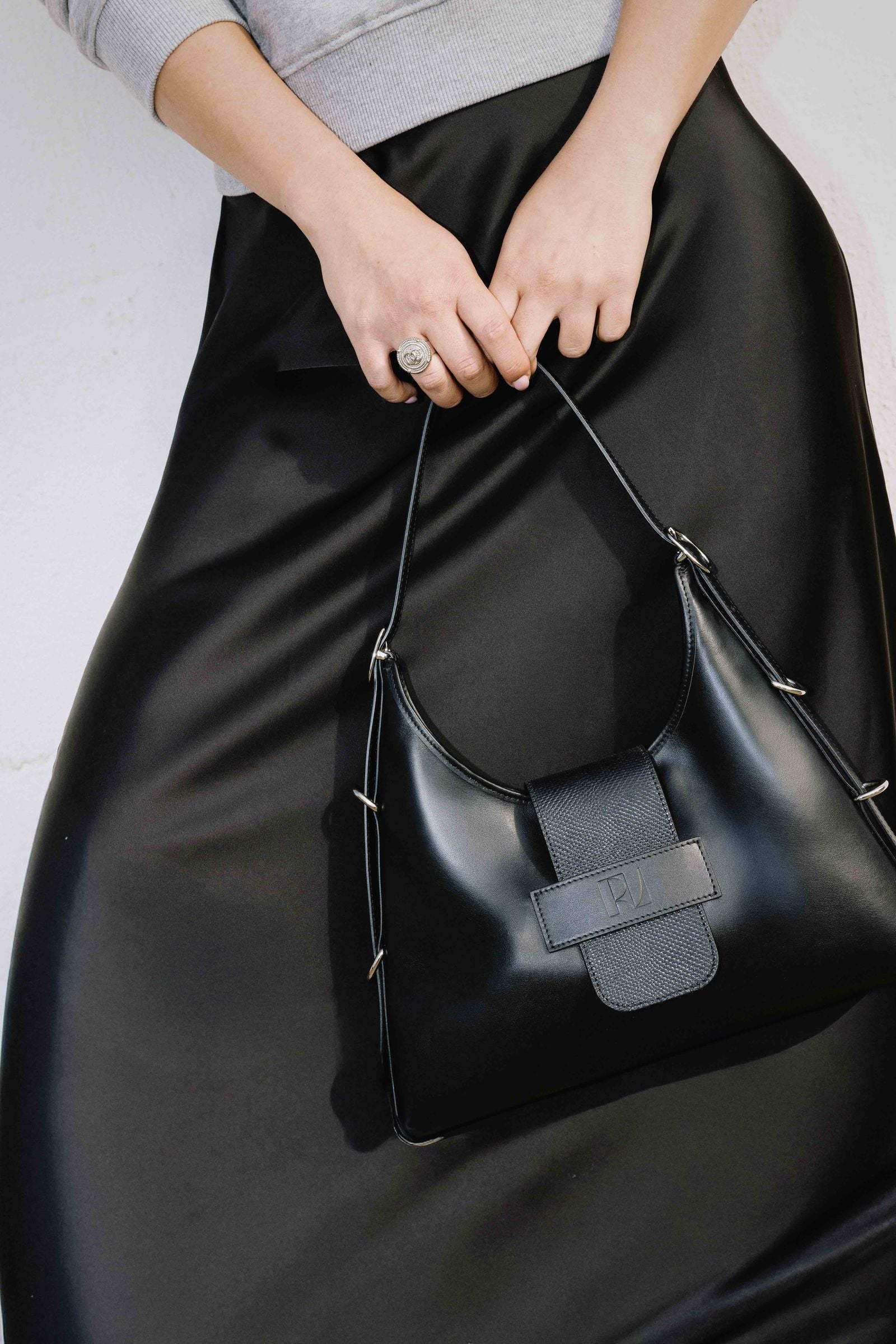 le sac fada taille M noir karung et porté à la main par une jeune femme. elle porte une jupe fluide noir.