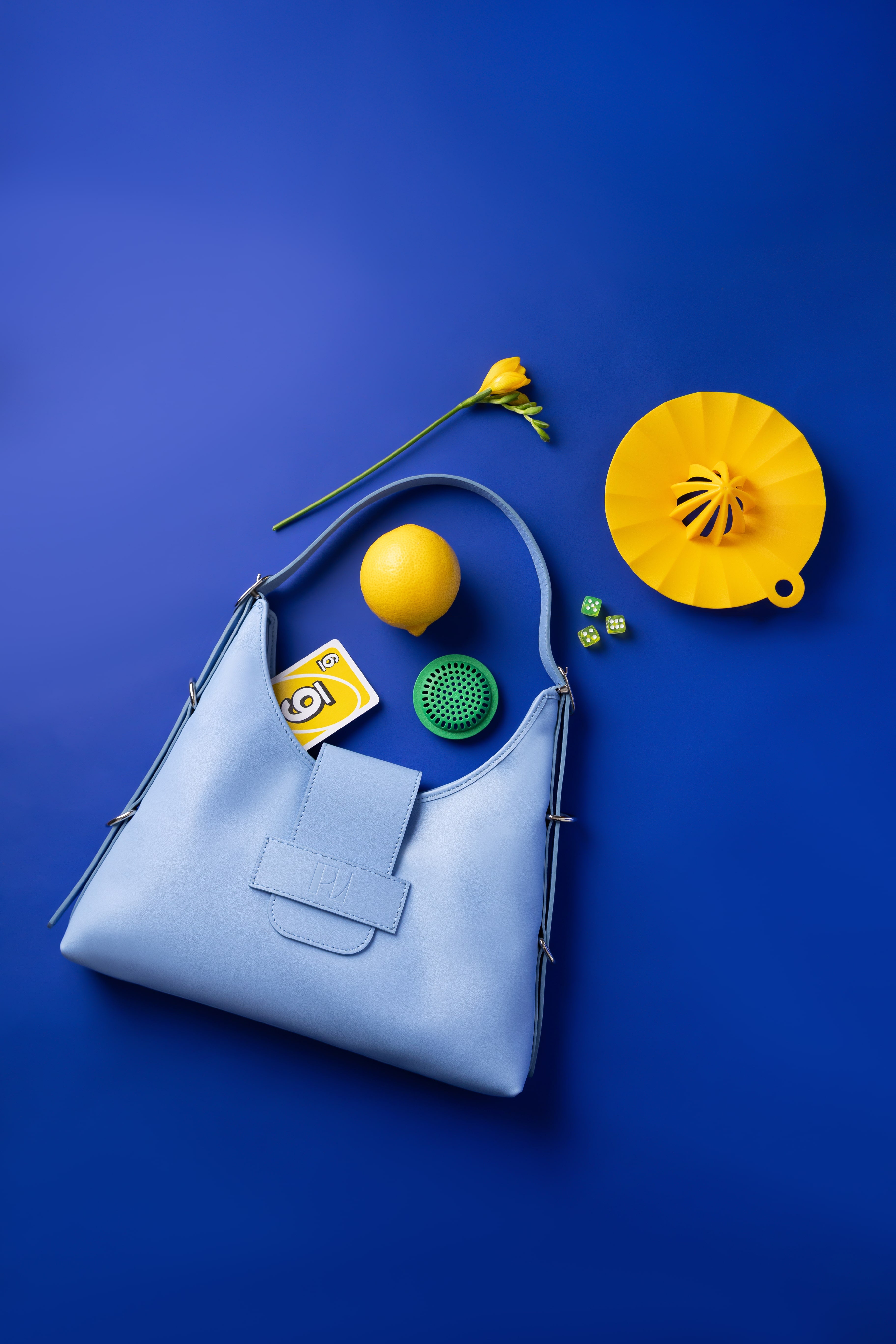 sac fada taille M bleu clair mis en scène sur un fond bleu indigo avec autour un citron, un presse citron un jonquille pour un effet jaune et bleu