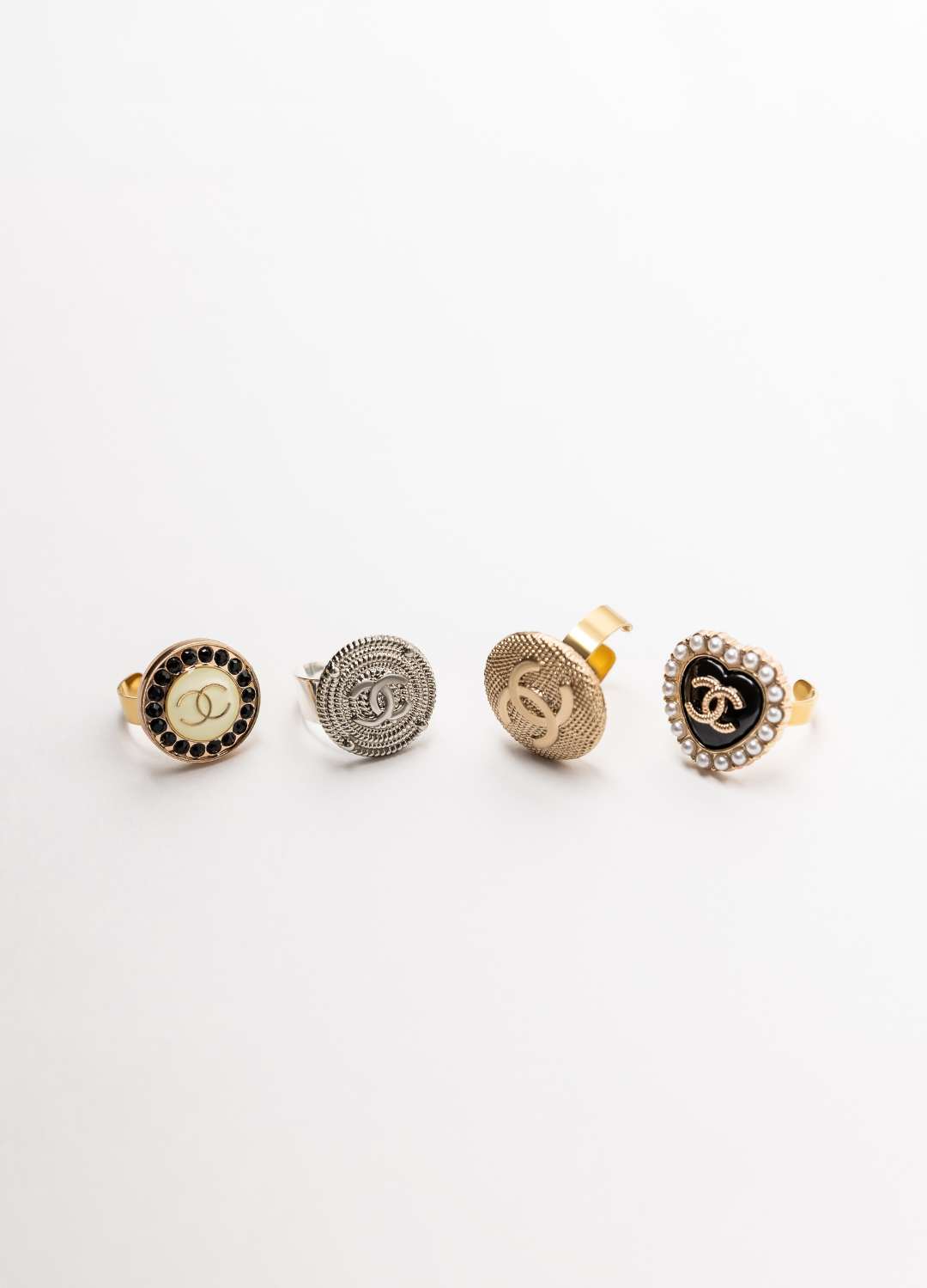 4 bagues fabriquées avec bouton posées sur une table fond blanc