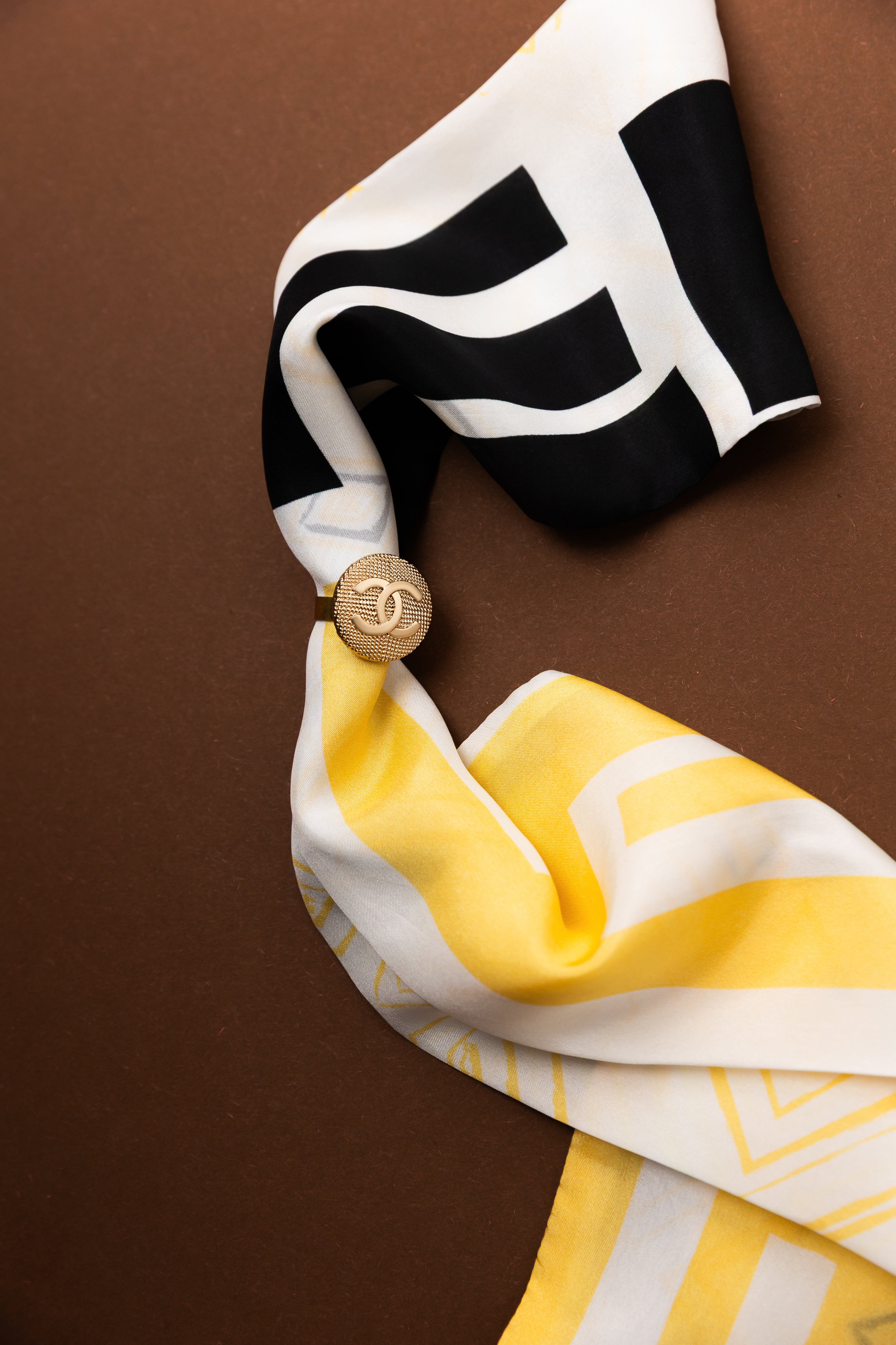 bouton chanel quadrillé doré autour d'un foulard
