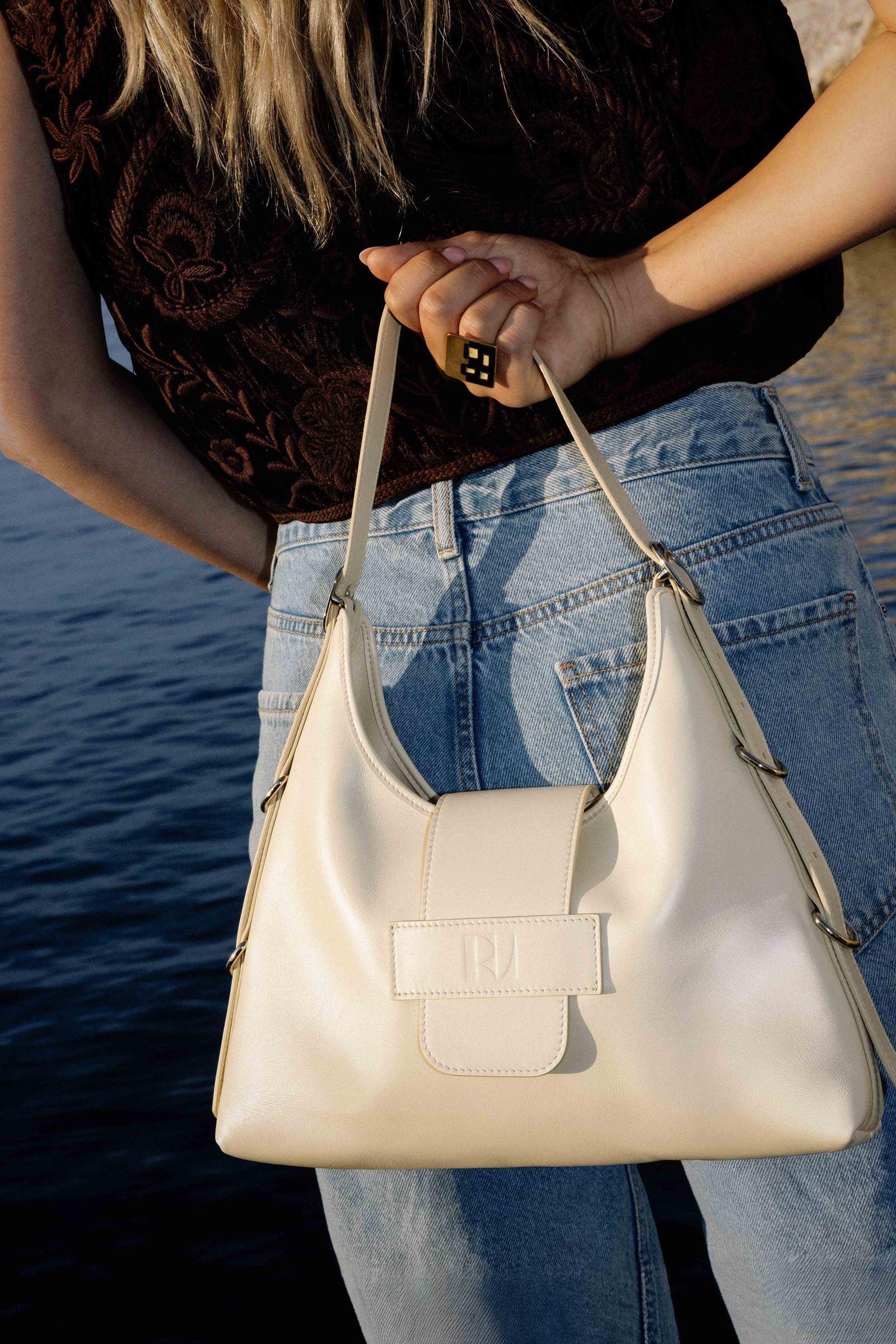 une jeune femme de dos porte à la main le sac fada taille M jaune pale. elle est face à la mer