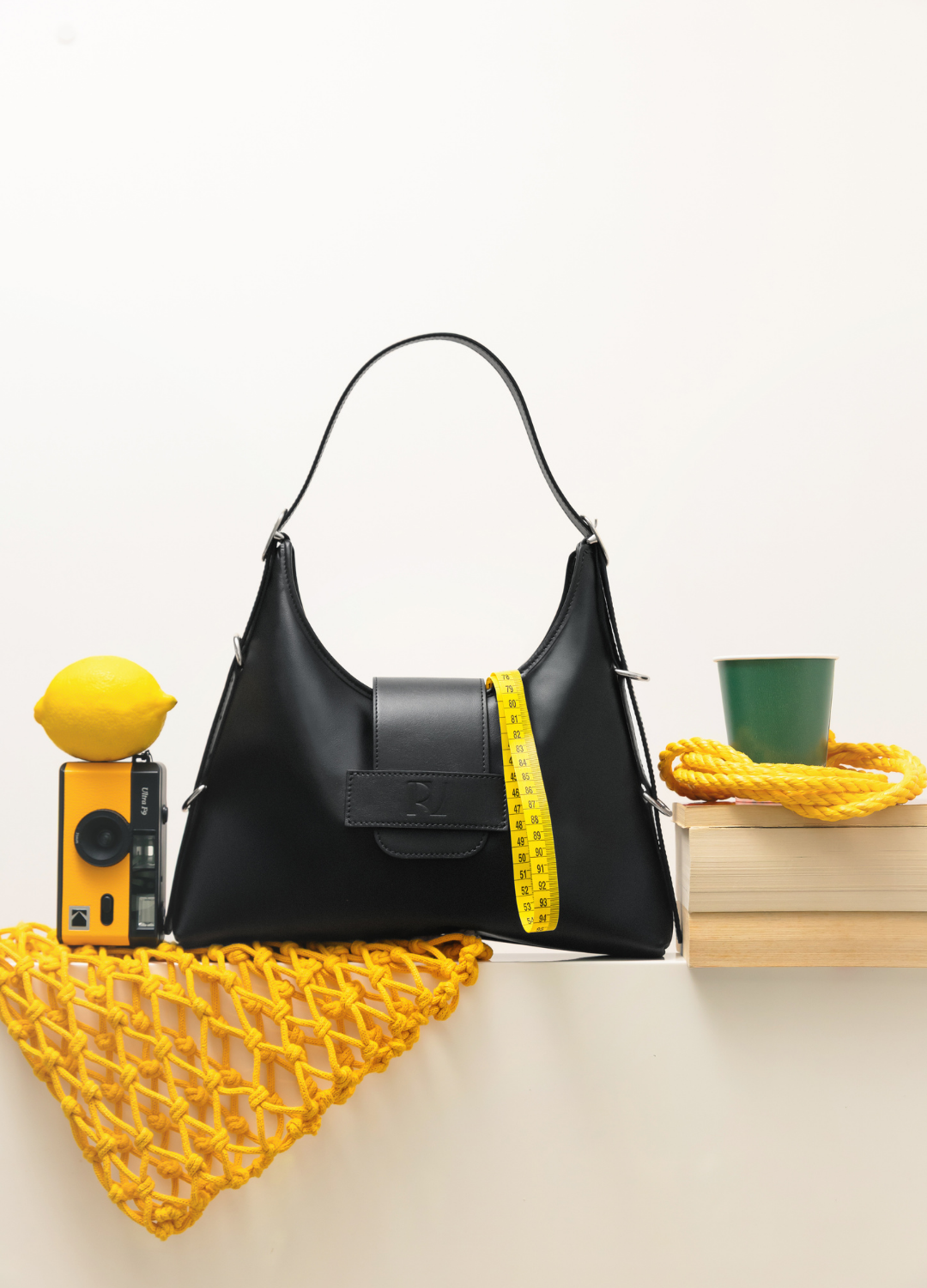 sac fada taille M noir mis en scène sur une table avec citron, appareil photo, filet jaunes